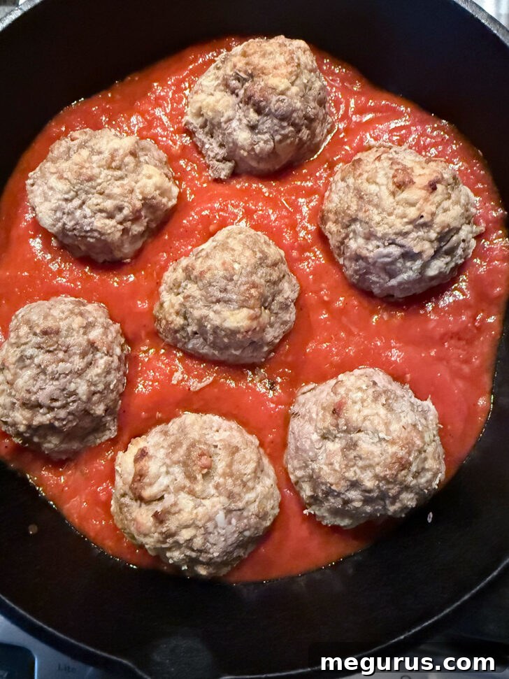 Cooked meatballs nestled in marinara sauce within the skillet.