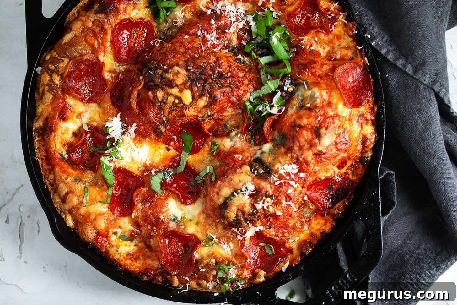 Crispy, bubbly focaccia pizza with pepperoni and cheese in a cast iron skillet, freshly baked.
