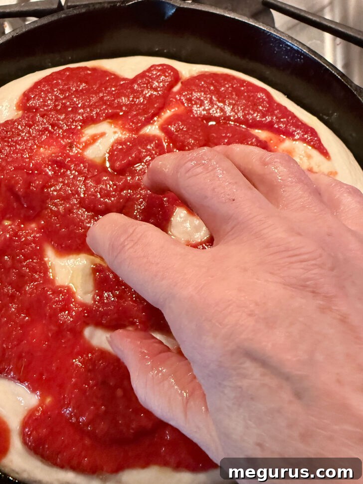 Fingertips dimpling the focaccia dough, creating characteristic indentations on the surface.