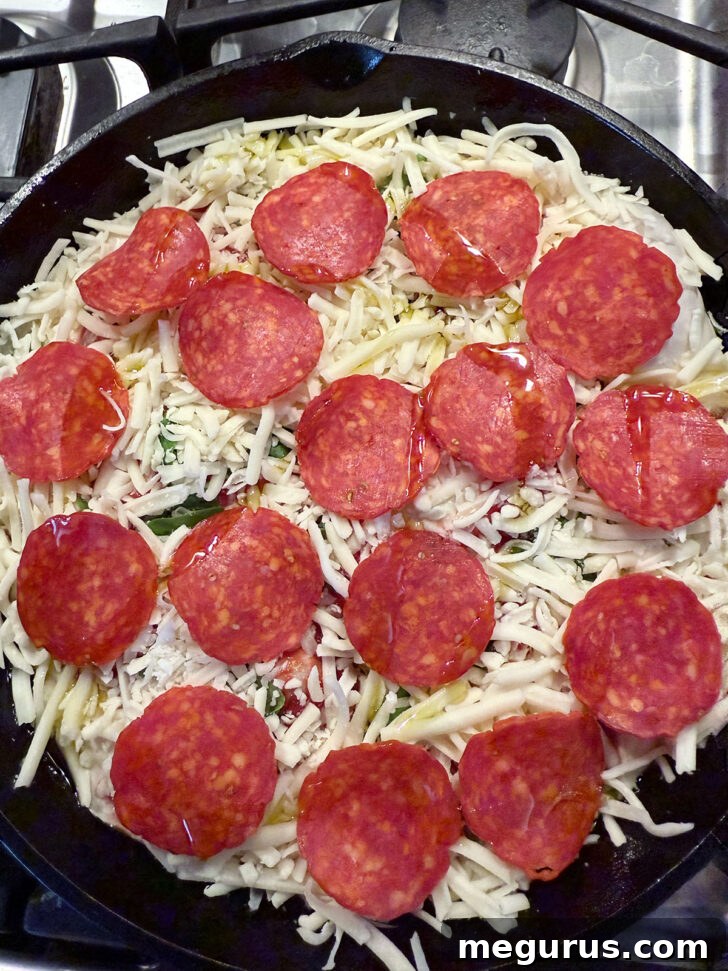 Focaccia pizza generously topped with shredded cheese and pepperoni slices, ready for baking.
