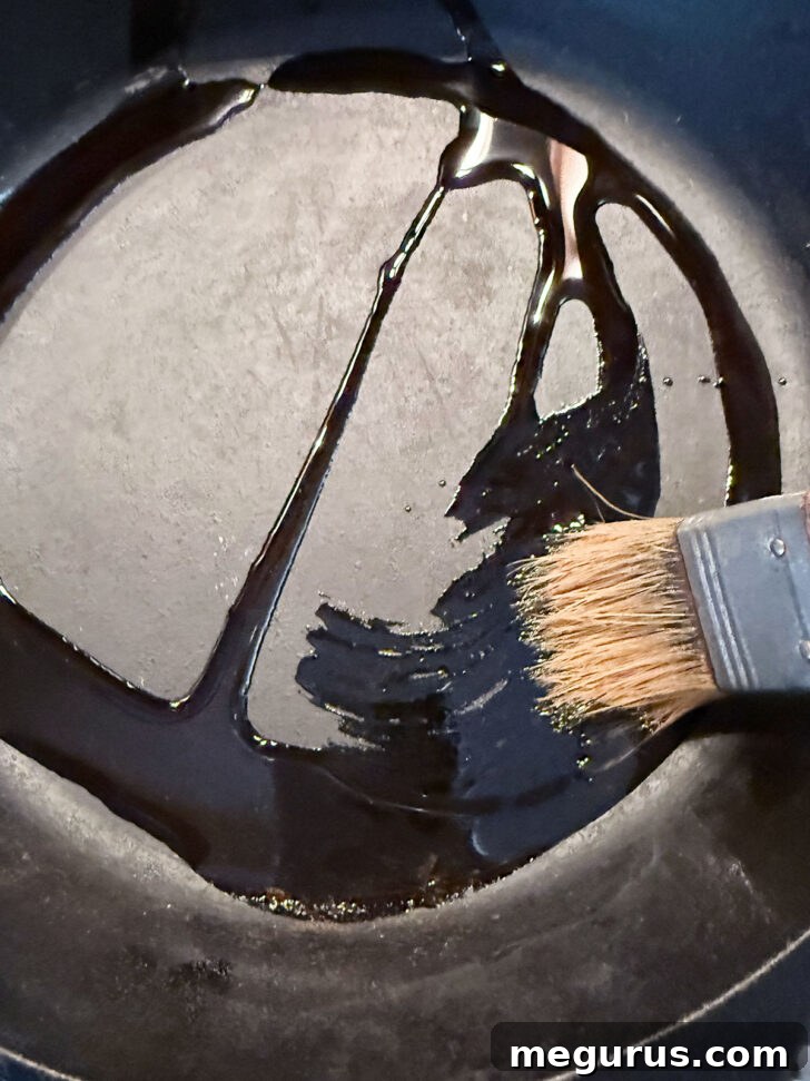 Brushing a generous amount of olive oil over the bottom and sides of a cast iron skillet.