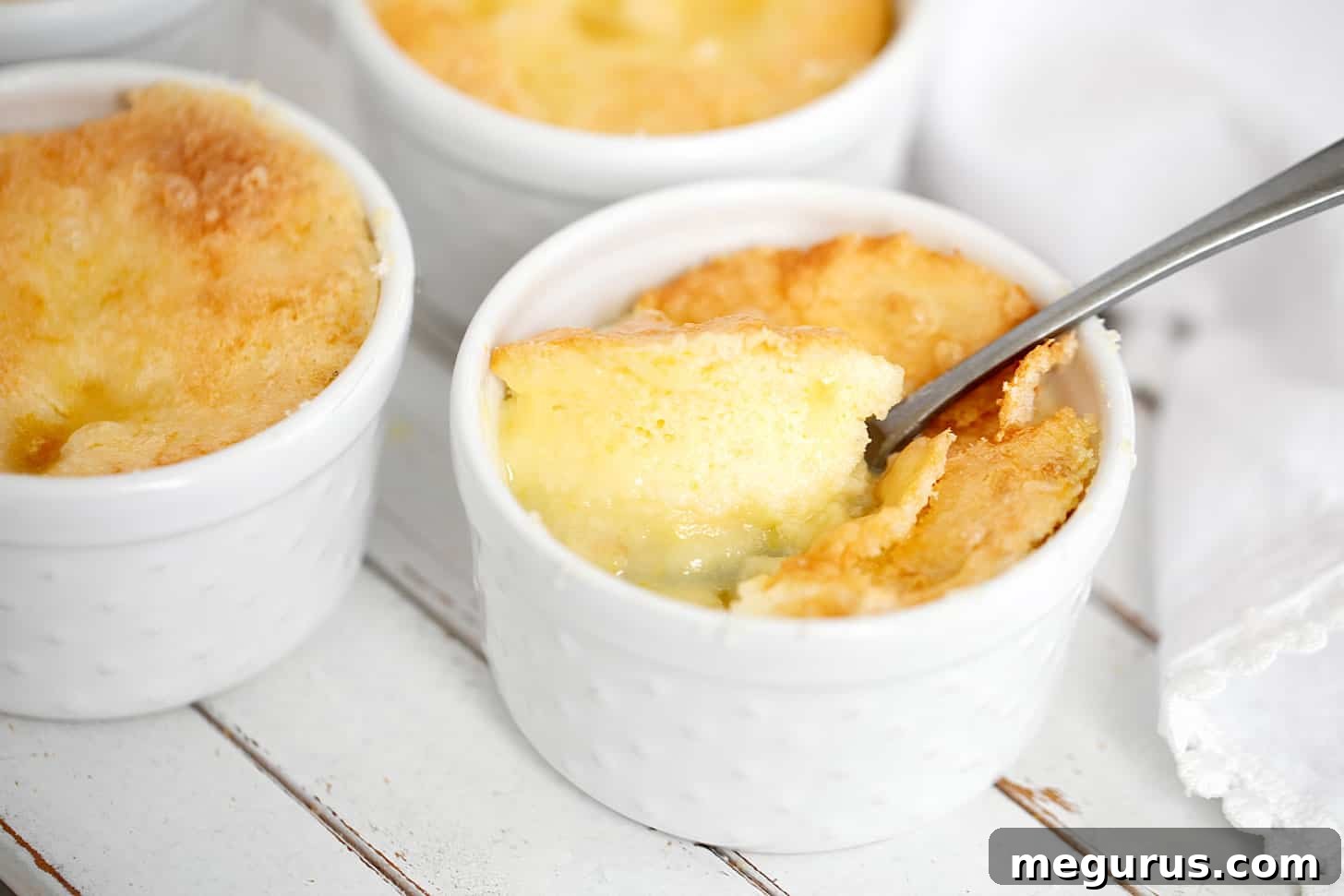 Individual Lemon Pudding Cake Pies in ramekins, ready to be enjoyed with a spoon.