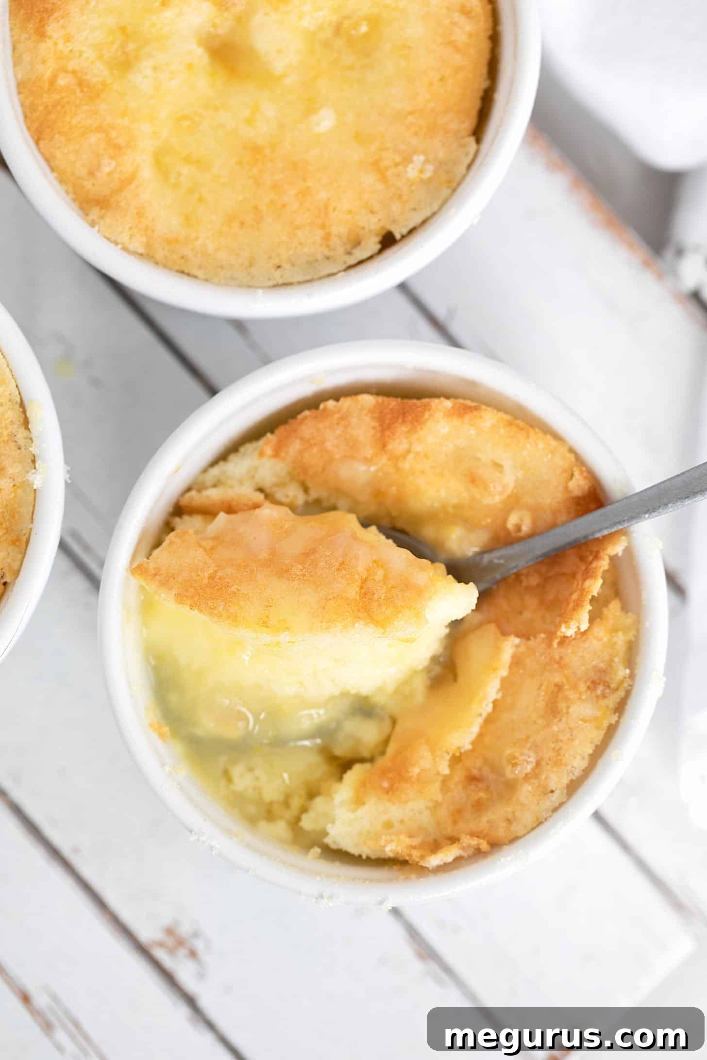 Lemon Pudding Cake Pie in individual ramekins, served with a spoon, highlighting the golden crust.
