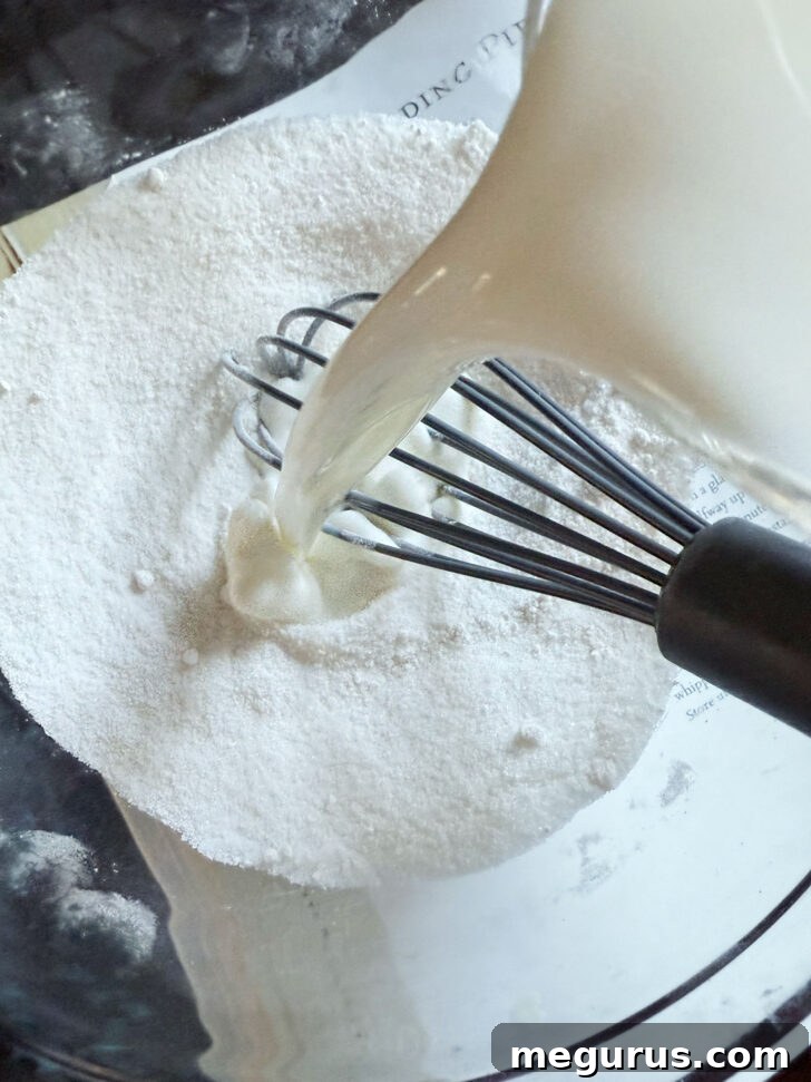 Adding milk to dry ingredients in mixing bowl.