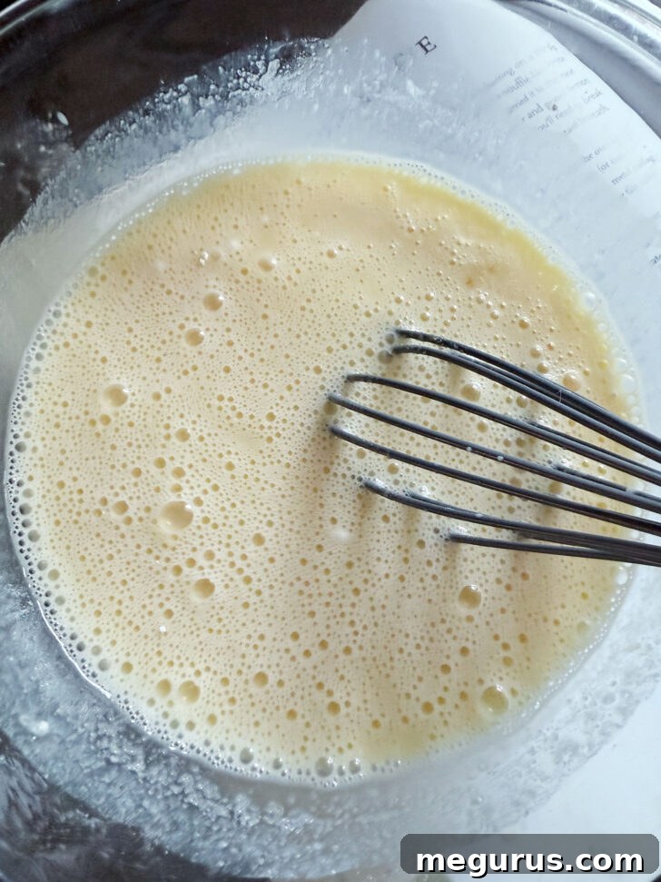 Whisking the egg yolks into the batter mixture.