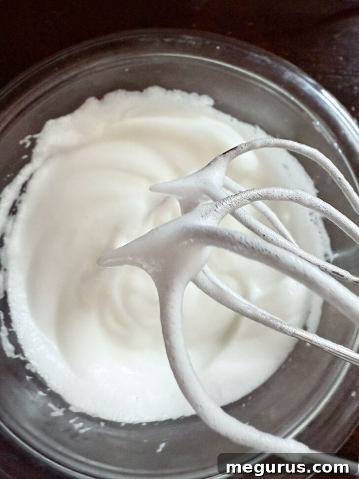 Beaten egg whites showing stiff peaks, essential for the cake's lift.