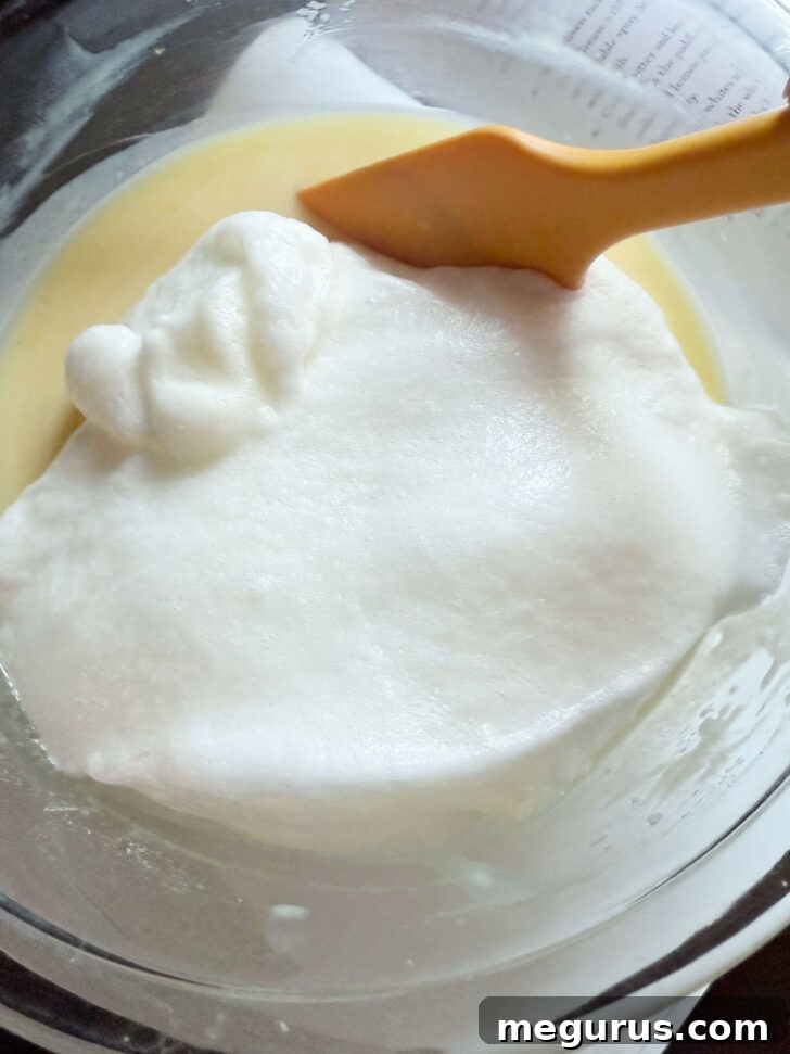 Stiff egg whites being added to the lemon pudding batter.