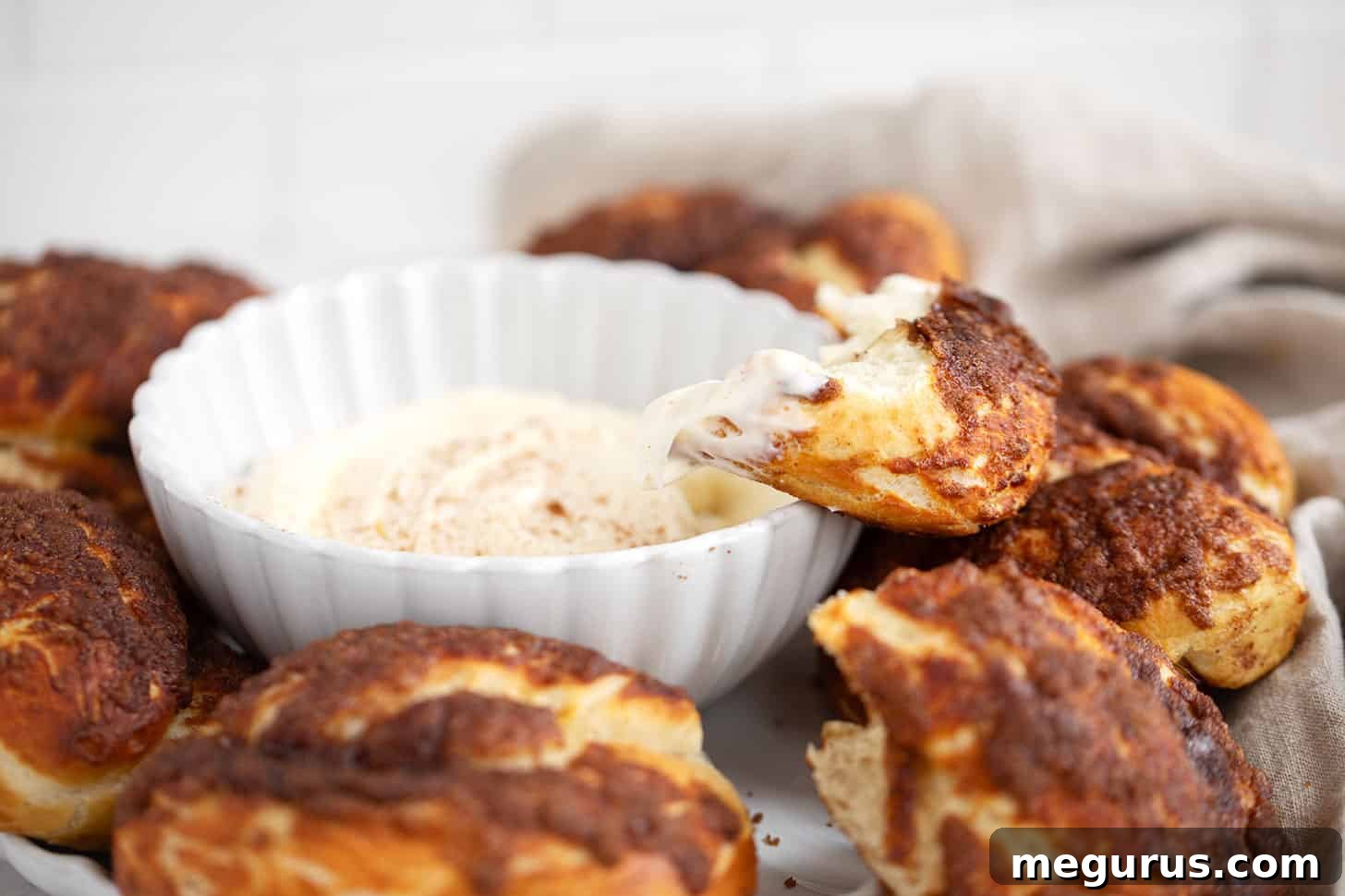 Freshly baked cinnamon crunch soft pretzels served with a sweet cream cheese dip on a wooden board.