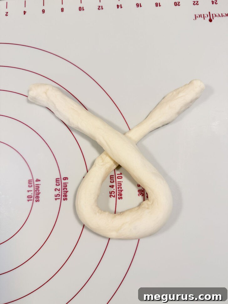Crossing over the ends of the U-shaped dough rope to form an X.
