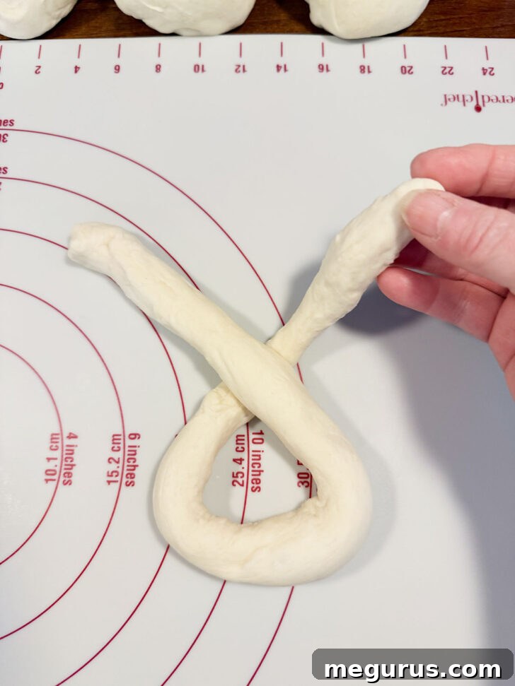 Grabbing the right end of the crossed dough rope.
