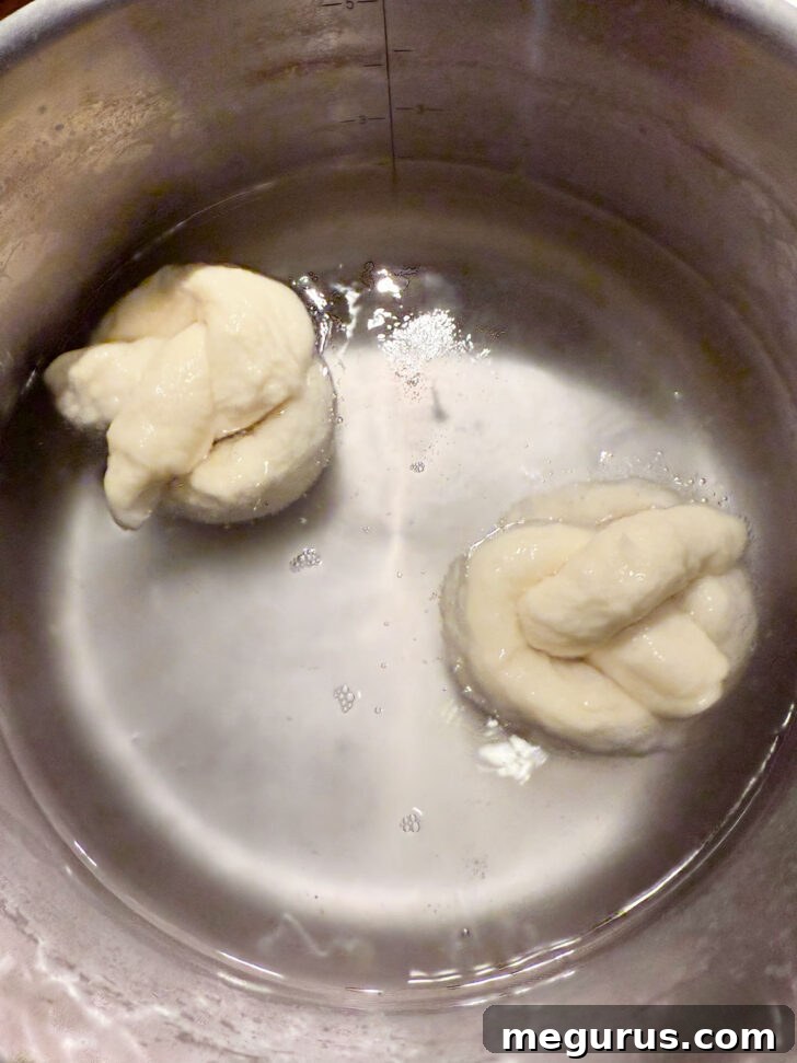 Boiling two pretzels in a pot of baking soda solution.