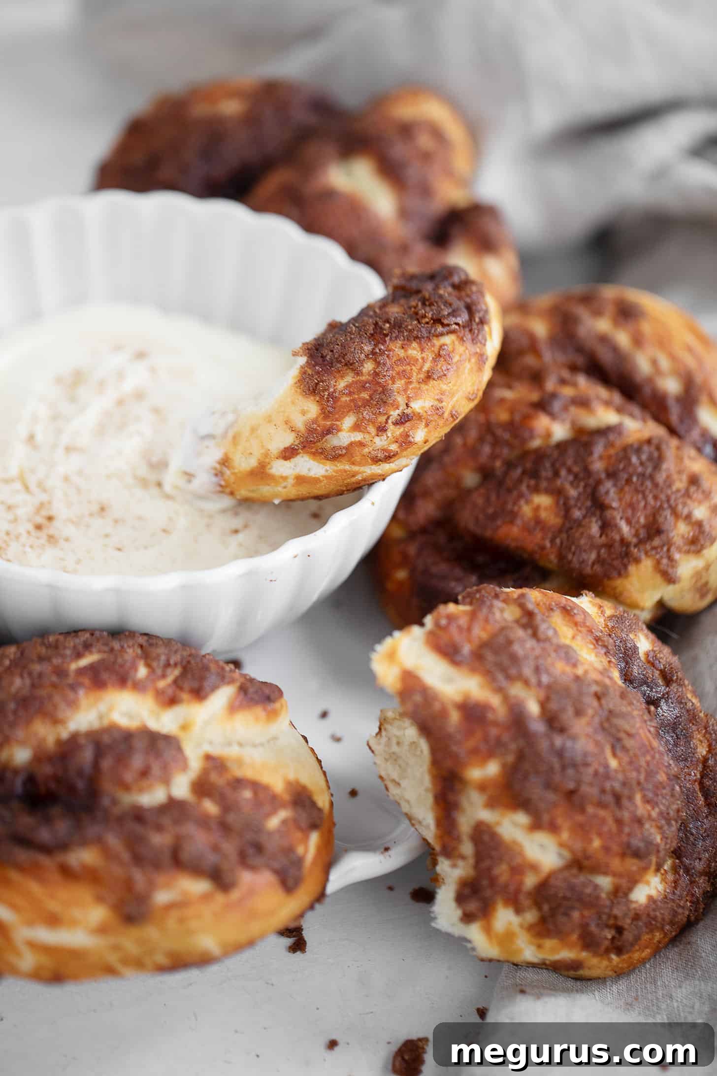 Close-up of baked cinnamon crunch soft pretzels and cream cheese dip.