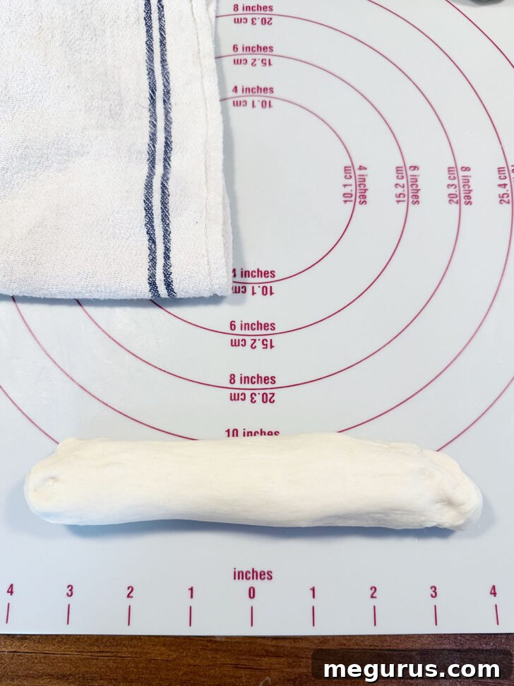 Starting to roll a dough ball into a long rope shape.