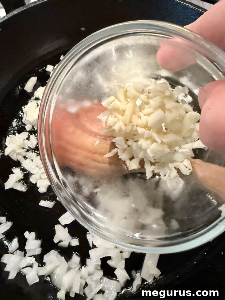 Adding garlic to onion in the skillet.