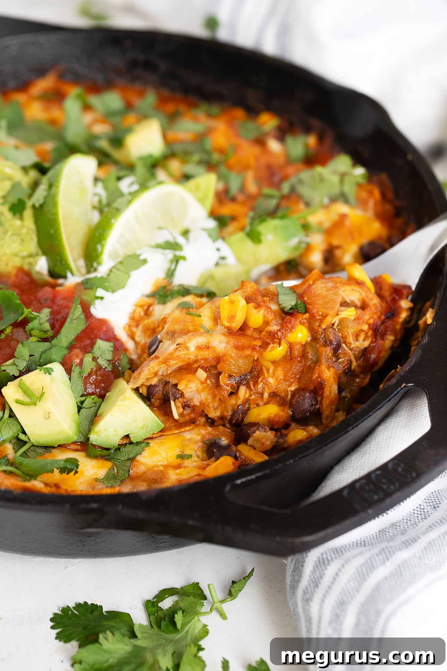 Close-up of baked chicken enchilada skillet with melted cheese and fresh cilantro.