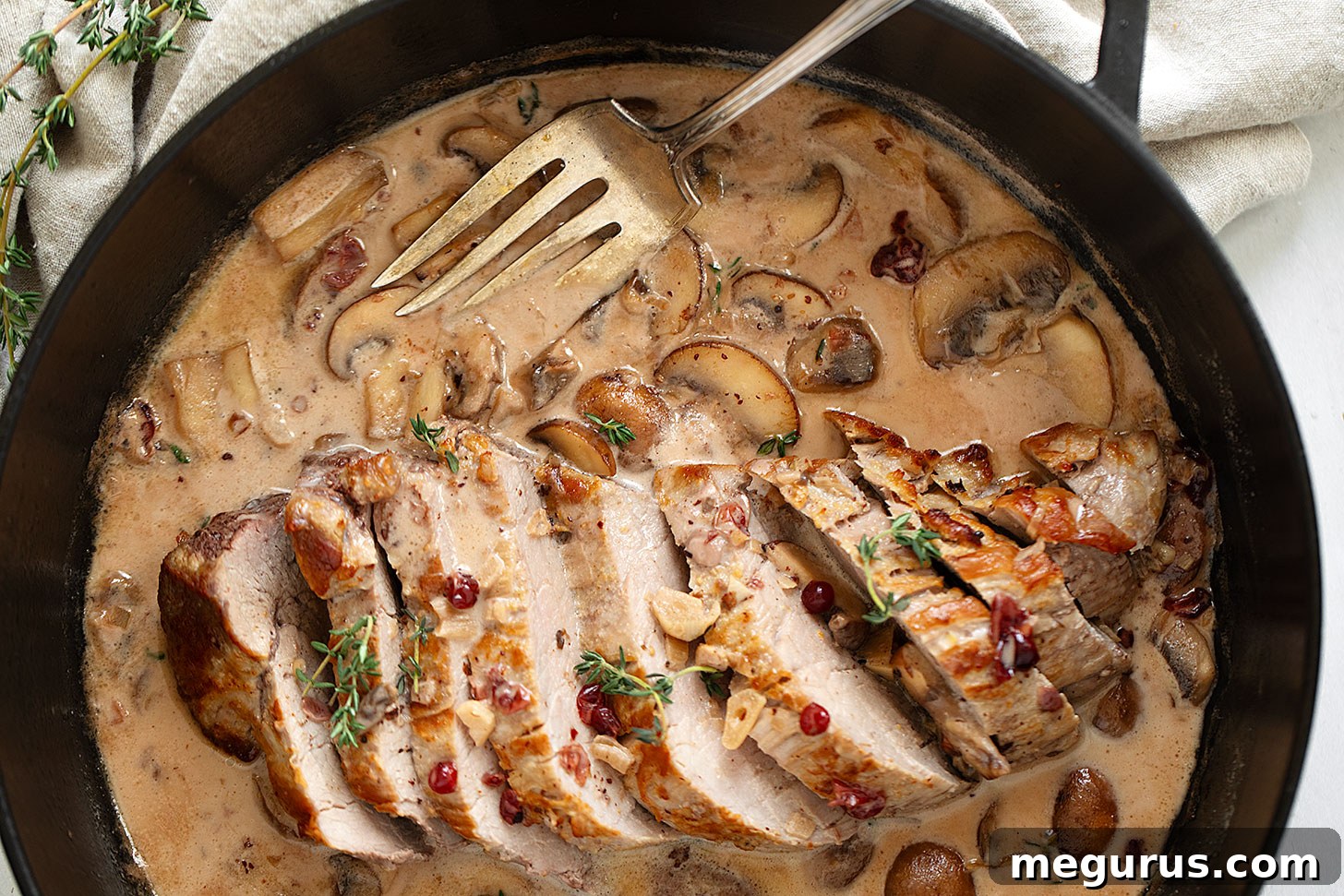 Pork tenderloin with a creamy mushroom and lingonberry jam sauce in skillet.