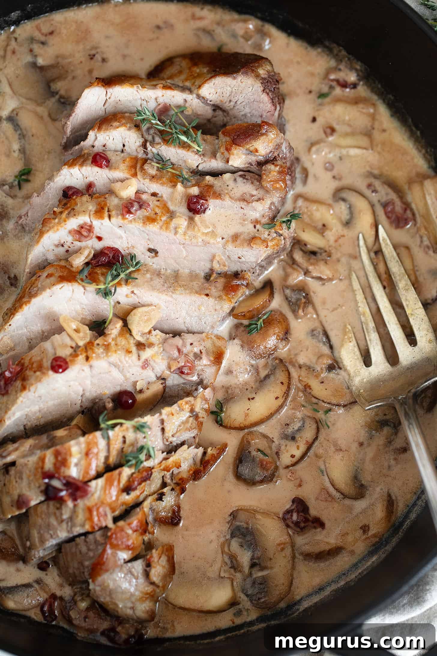 Pork tenderloin with a creamy mushroom and lingonberry jam sauce in skillet.