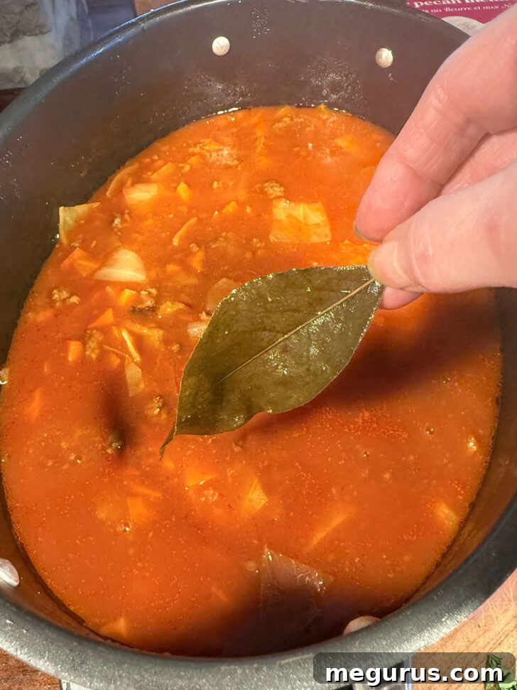 A bay leaf being removed from the cooked cabbage roll soup.