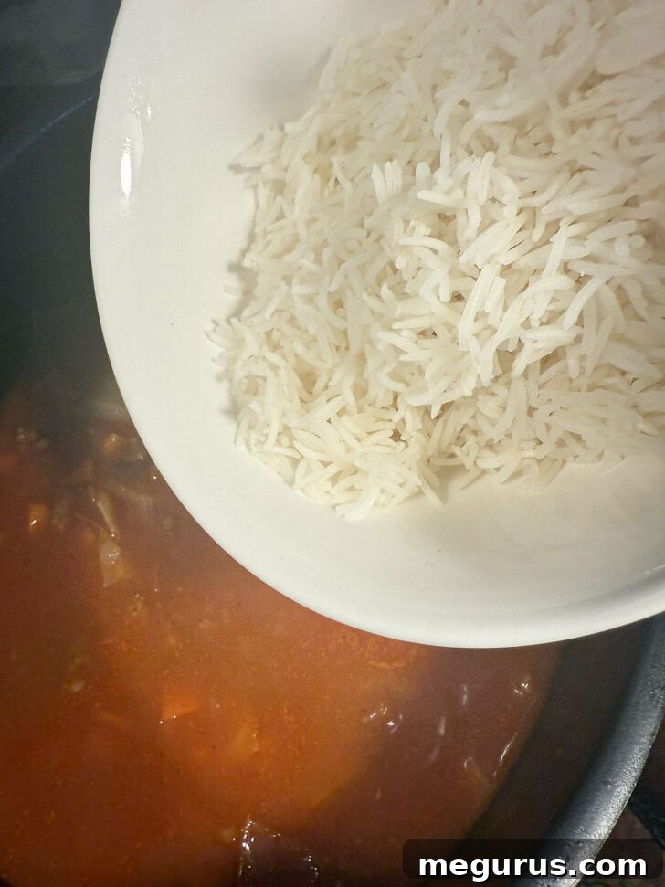 Cooked rice being stirred into the cabbage roll soup.