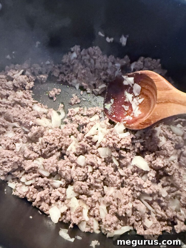 Cooked ground beef and softened onions in a skillet.