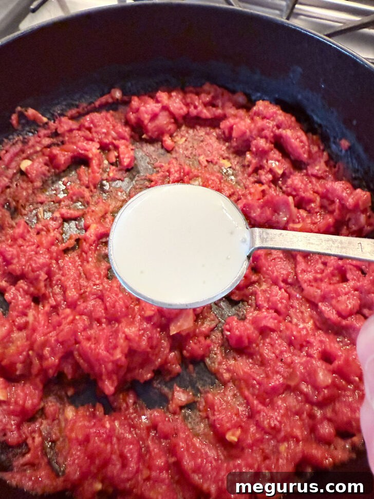 Adding cream to the skillet with the tomatoes.