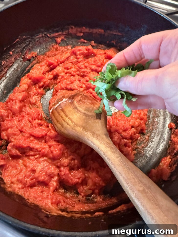 Adding some fresh basil to the vodka sauce.