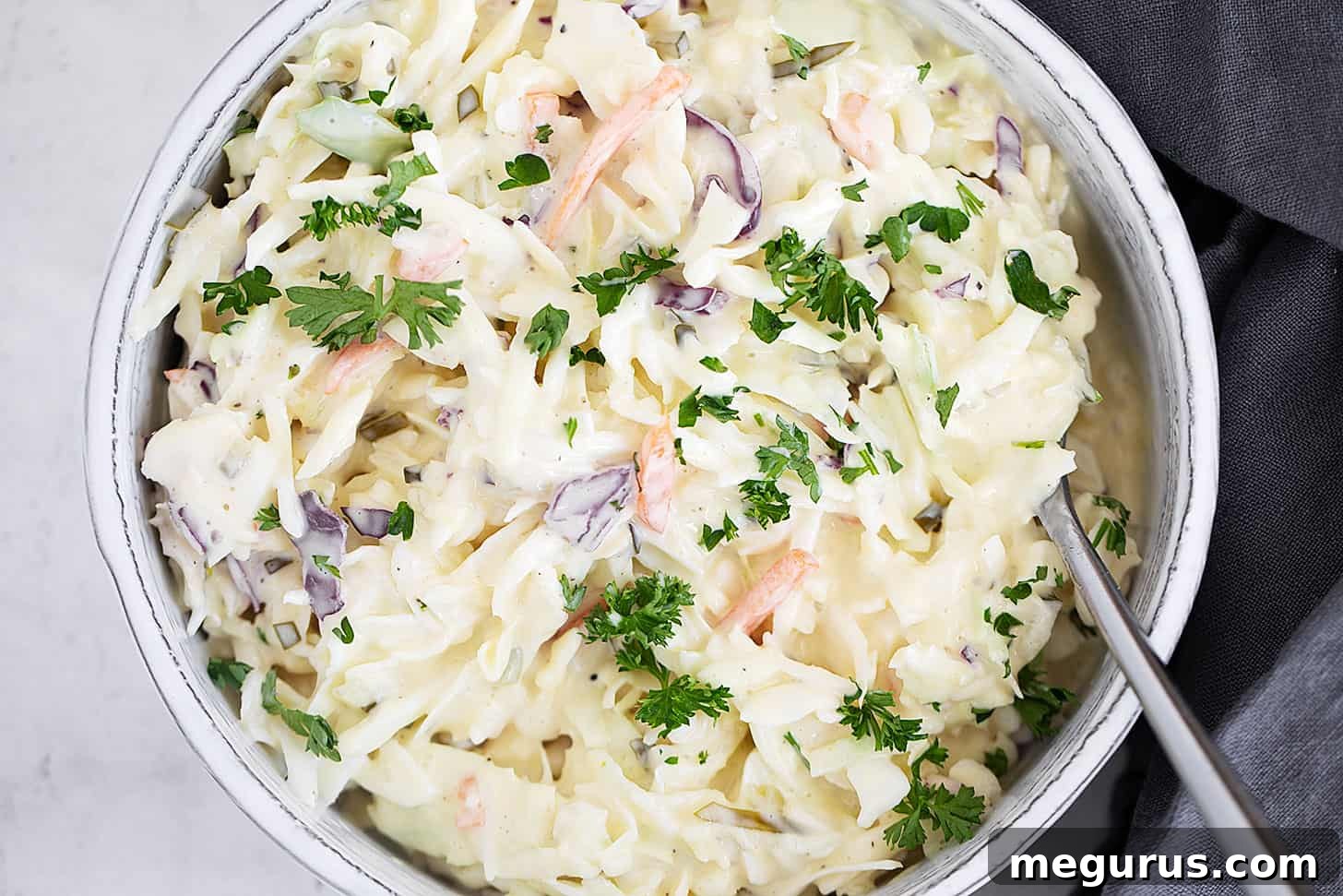 Pickle coleslaw in serving dish with spoon, ready to be enjoyed.
