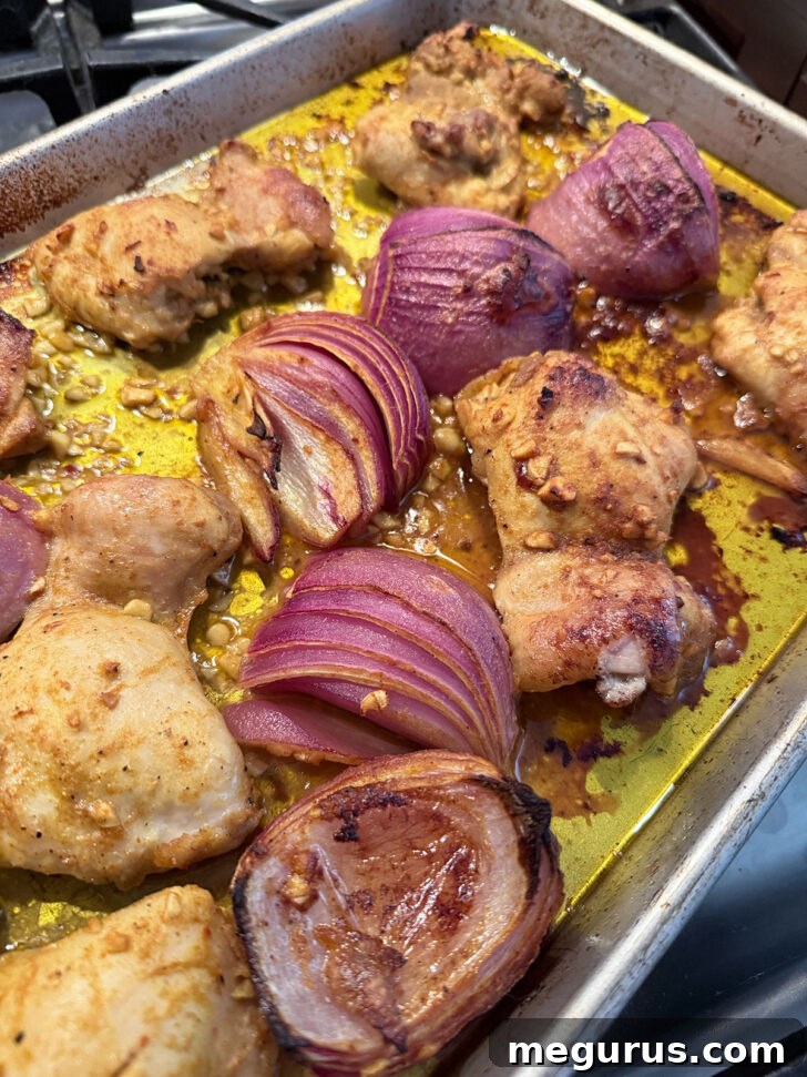 Roasted onion and chicken on baking sheet after baking, browned and crispy.