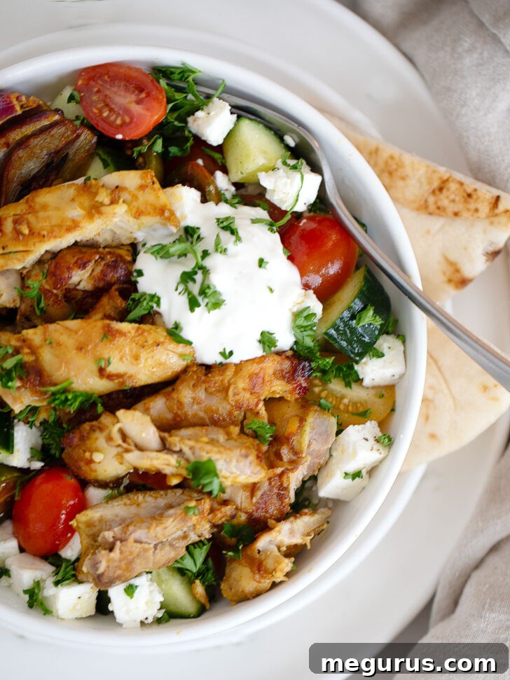 Finished chicken shawarma bowl, beautifully assembled with toppings and sauce.