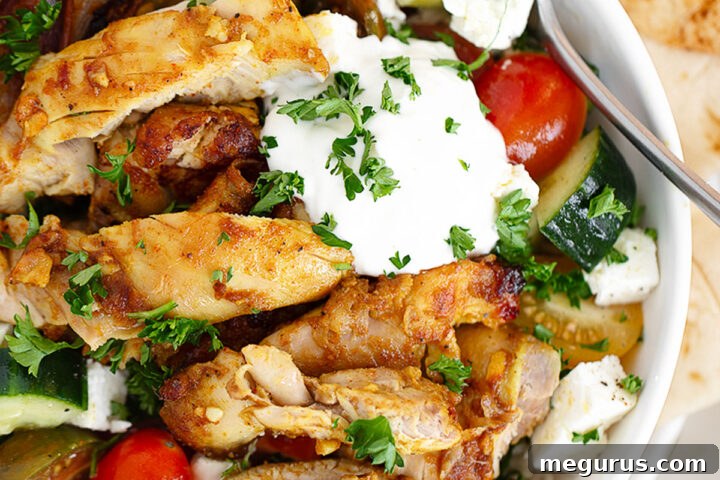 Chicken shawarma bowl with rice, tomatoes, cucumber and white sauce.
