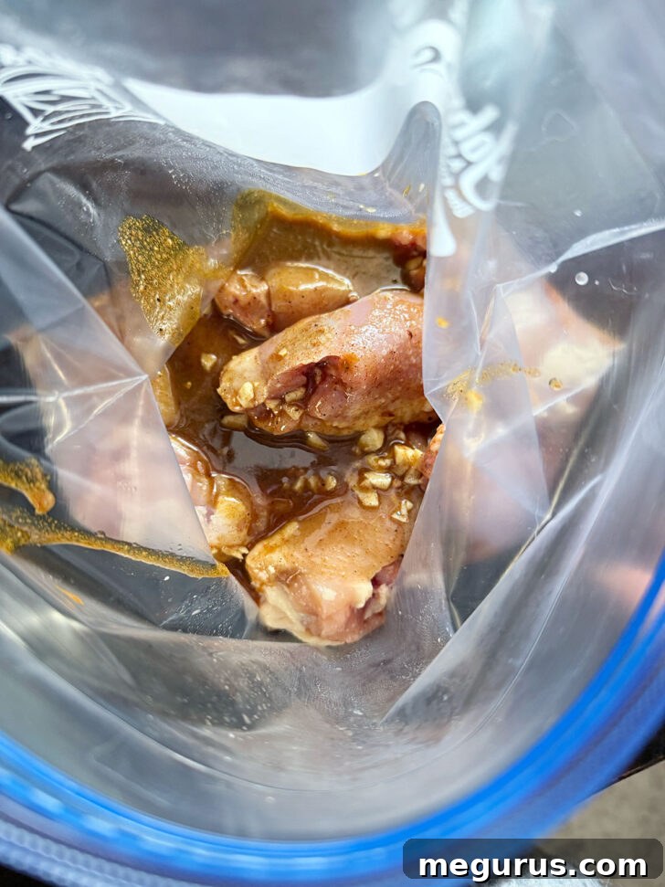 Marinade added to chicken thighs in a zipper bag for even coating.