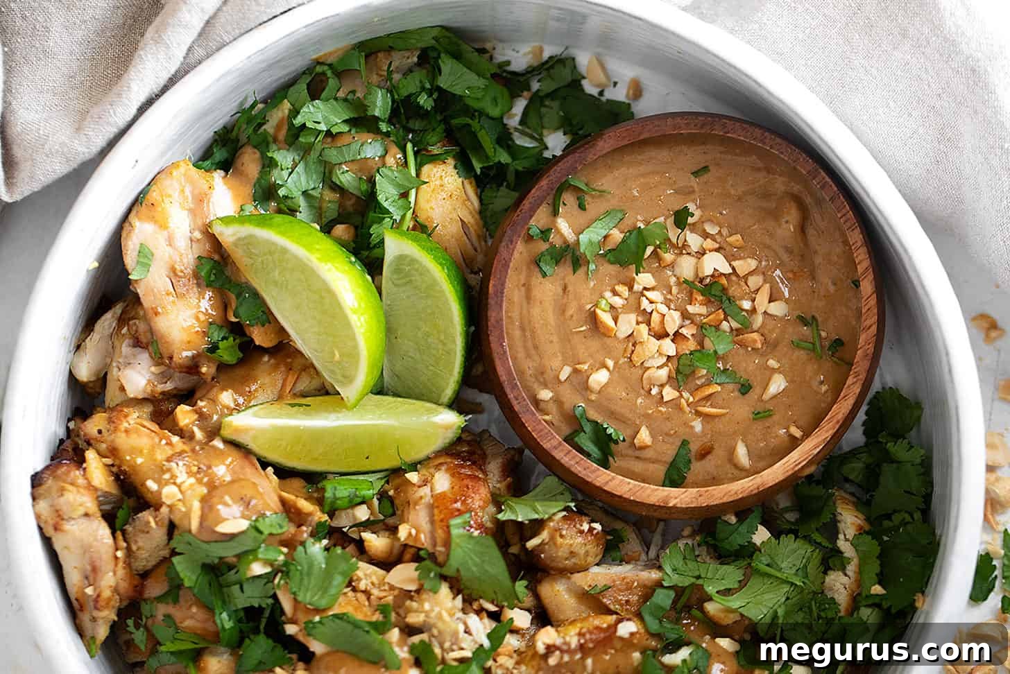Lime and coconut chicken with peanut sauce in serving bowl, garnished with fresh cilantro and chopped peanuts.