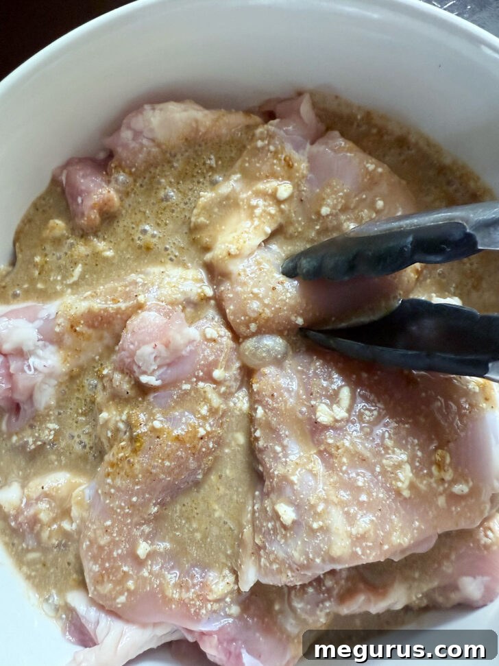 Tossing the boneless chicken thighs to ensure they are fully coated in the aromatic marinade.