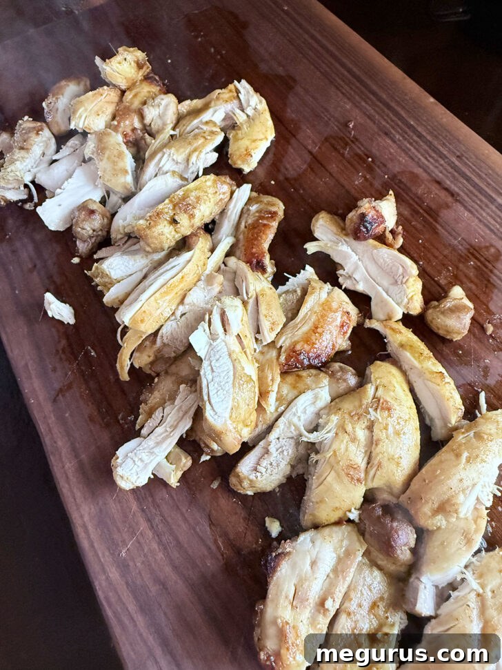 Perfectly sliced coconut chicken arranged on a cutting board, ready for serving with peanut sauce.