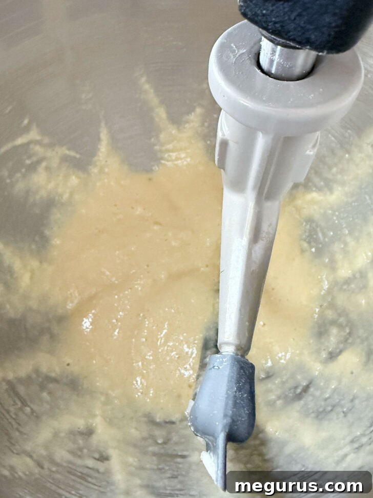Cake batter after eggs and vanilla have been mixed in, appearing smooth and creamy.