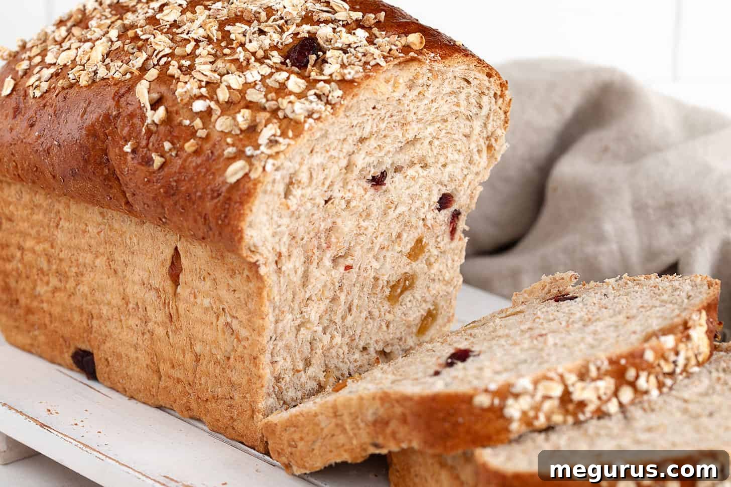 Harvest grain bread freshly sliced on a rustic cutting board, showcasing its rich texture and fruit inclusions.