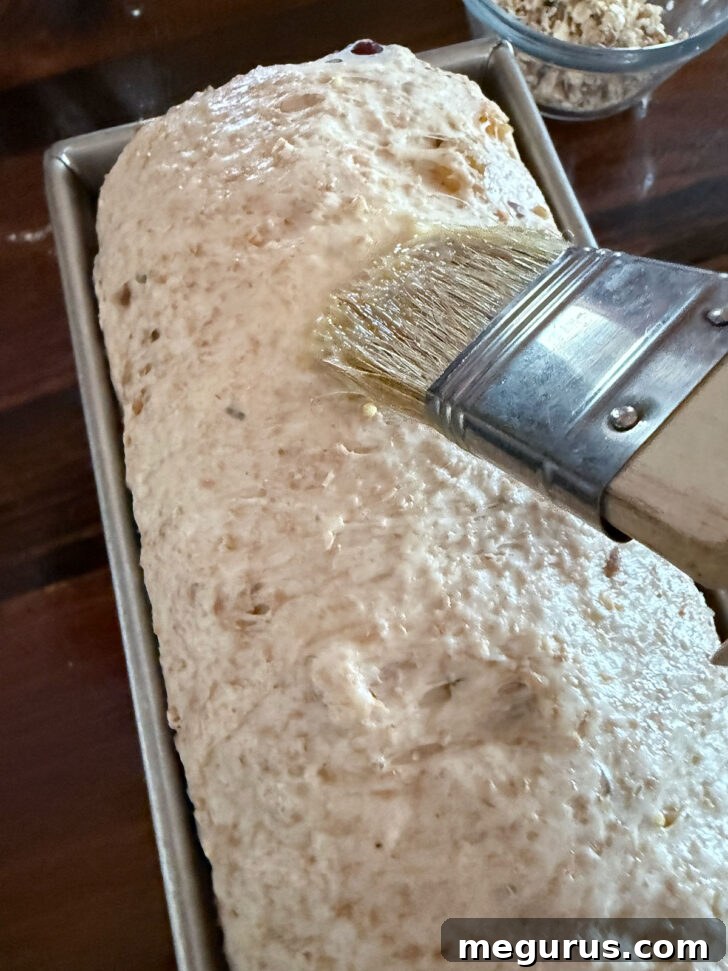 Brushing the risen loaf with an egg wash before applying topping.