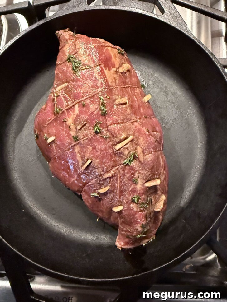 Marinated roast in a cast iron skillet before roasting.