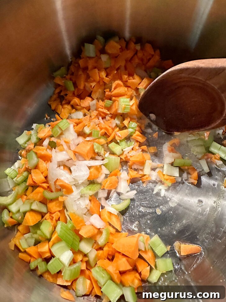 Sautéing diced onion, carrots, and celery in a large soup pot.