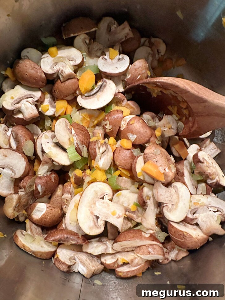 Sliced mushrooms added to the sautéed vegetables in the soup pot.