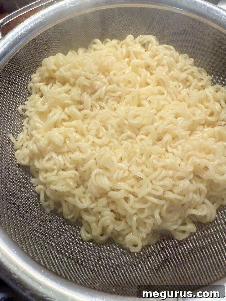 Cooked ramen noodles being drained in a colander.