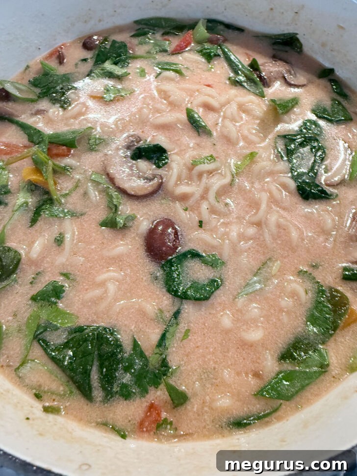 The finished spicy coconut ramen dish, ready to be served, in a large soup pot.