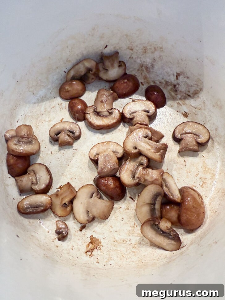 Sliced mushrooms browning in a large soup pot with a bit of oil.