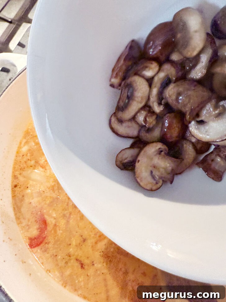 The previously cooked mushrooms being returned to the soup pot to simmer.