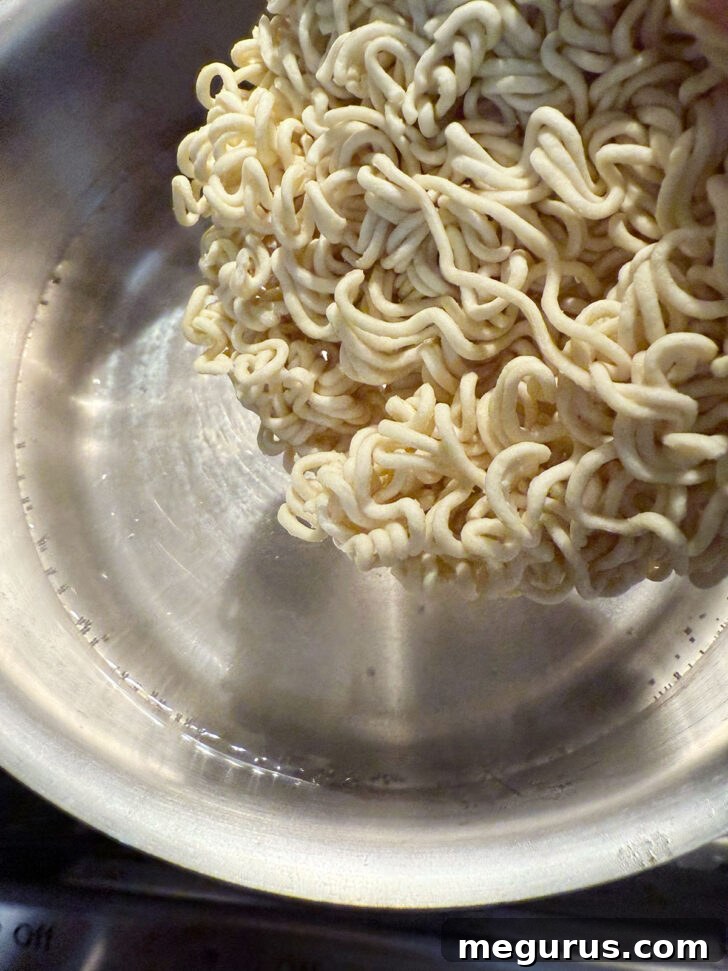 Dried ramen noodles being added to a pot of boiling water.