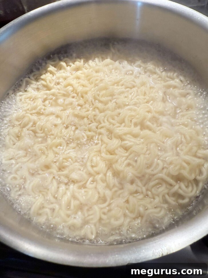 Boiling ramen noodles in a pot of water on the stovetop.