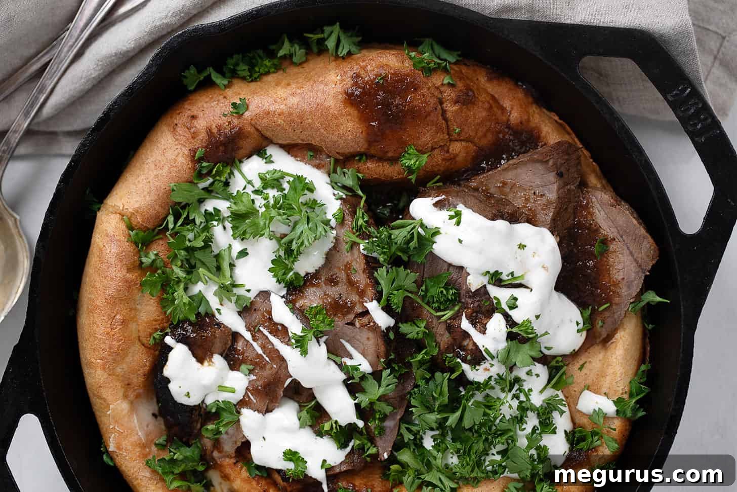 Leftover roast beef and Yorkshire pudding in cast iron skillet, garnished with fresh parsley.