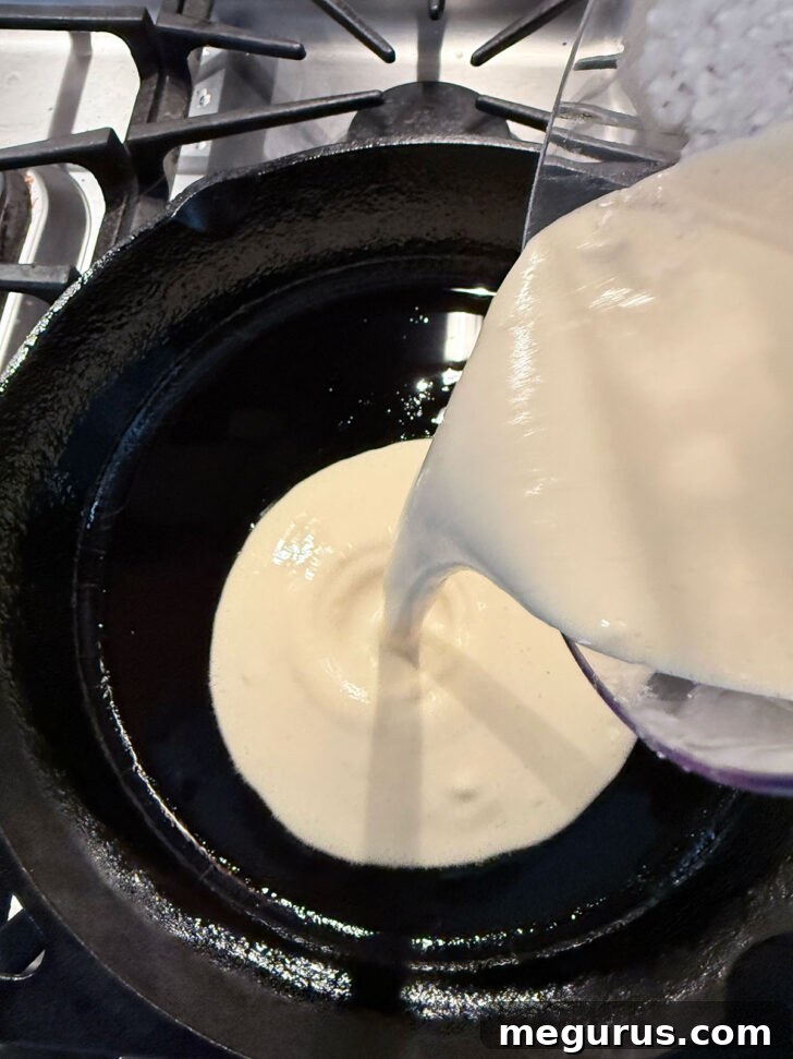 Adding Yorkshire pudding batter to the hot skillet.