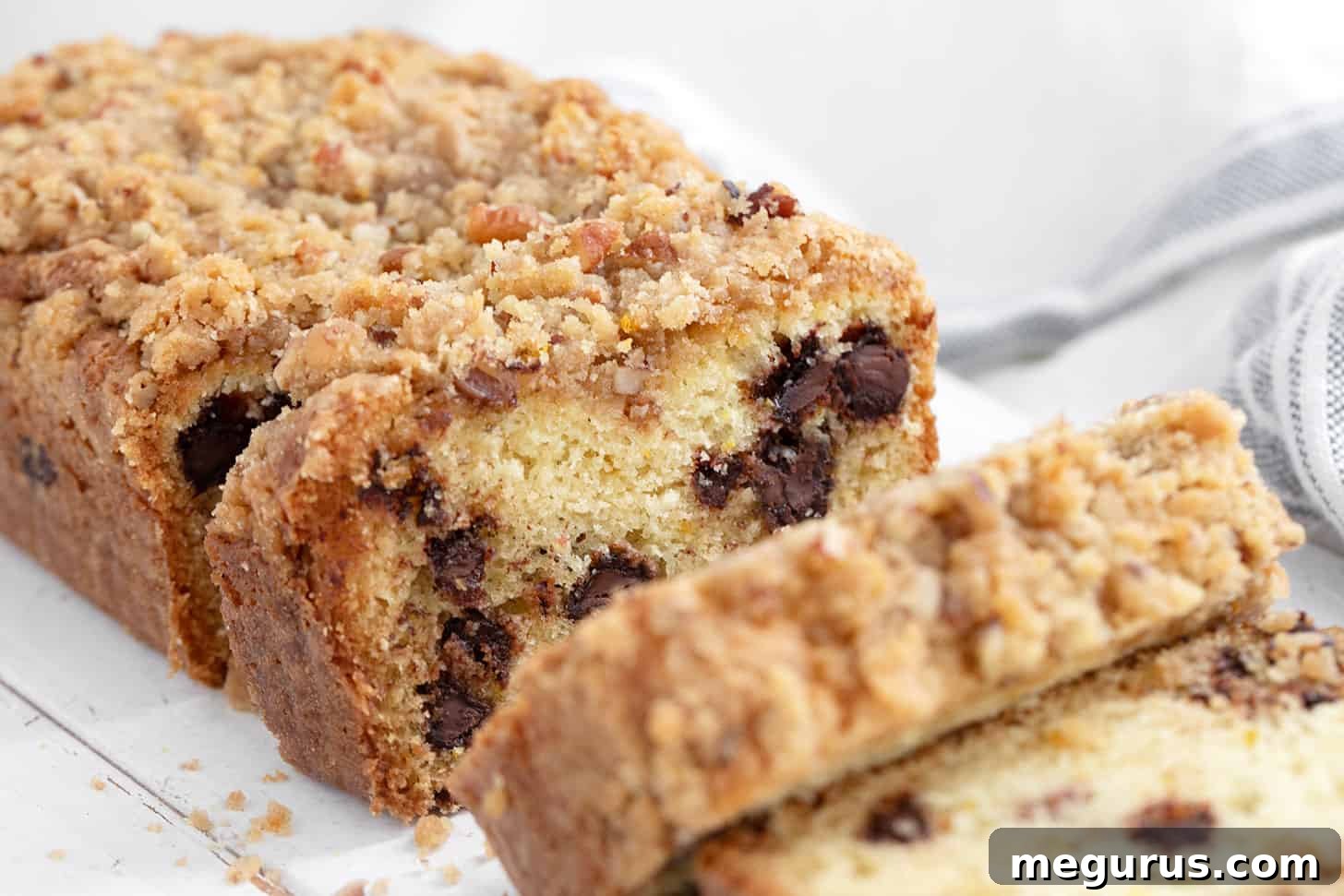 Freshly baked chocolate chip coffee cake loaf, perfectly sliced to reveal its moist interior and generous chocolate chips, resting on a rustic cutting board, ready to be enjoyed.