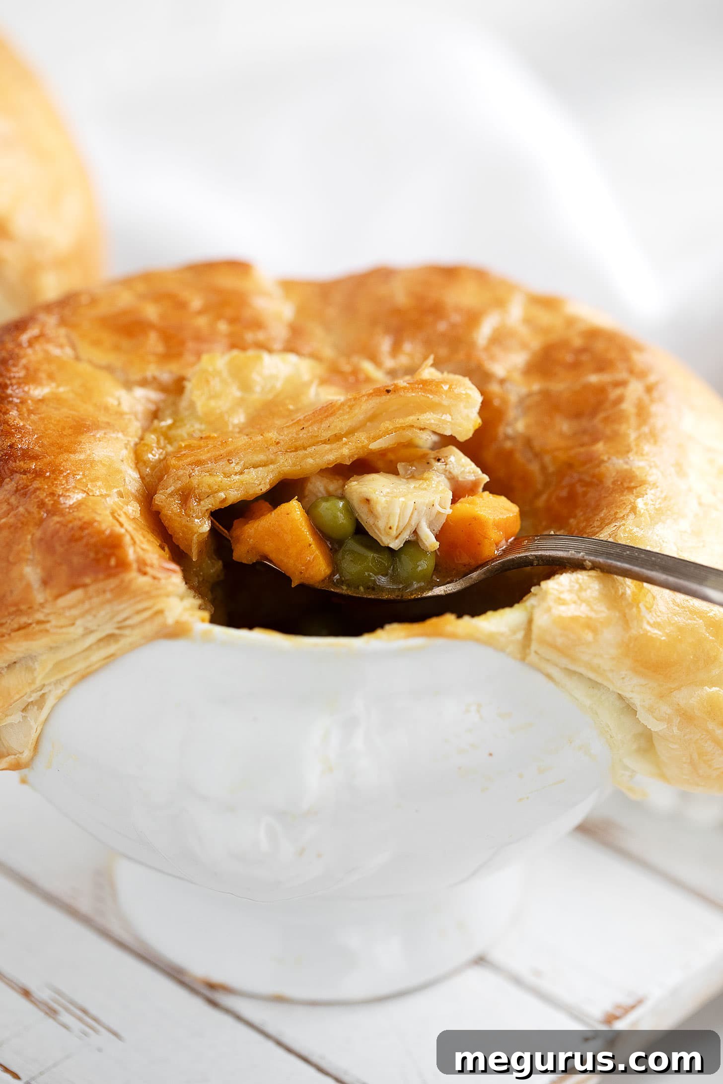 Close-up of a serving of curried chicken pot pie, showing the flaky crust and rich filling.